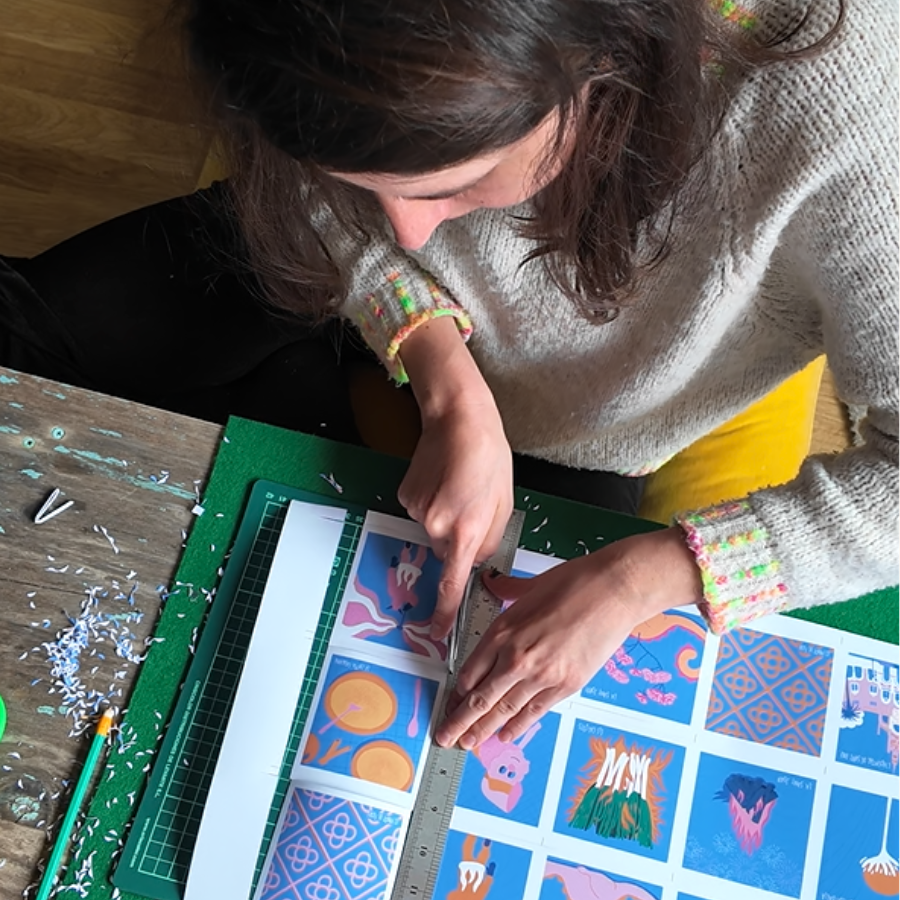 Amélie Decomble alias Amélimón en train de ttravailler dans son bureau. Elle découpe des illustrations qu'elle a faite elle même pour le clients skyscanner. Bureau trés joli, coloré. Illustration sur Barcelone