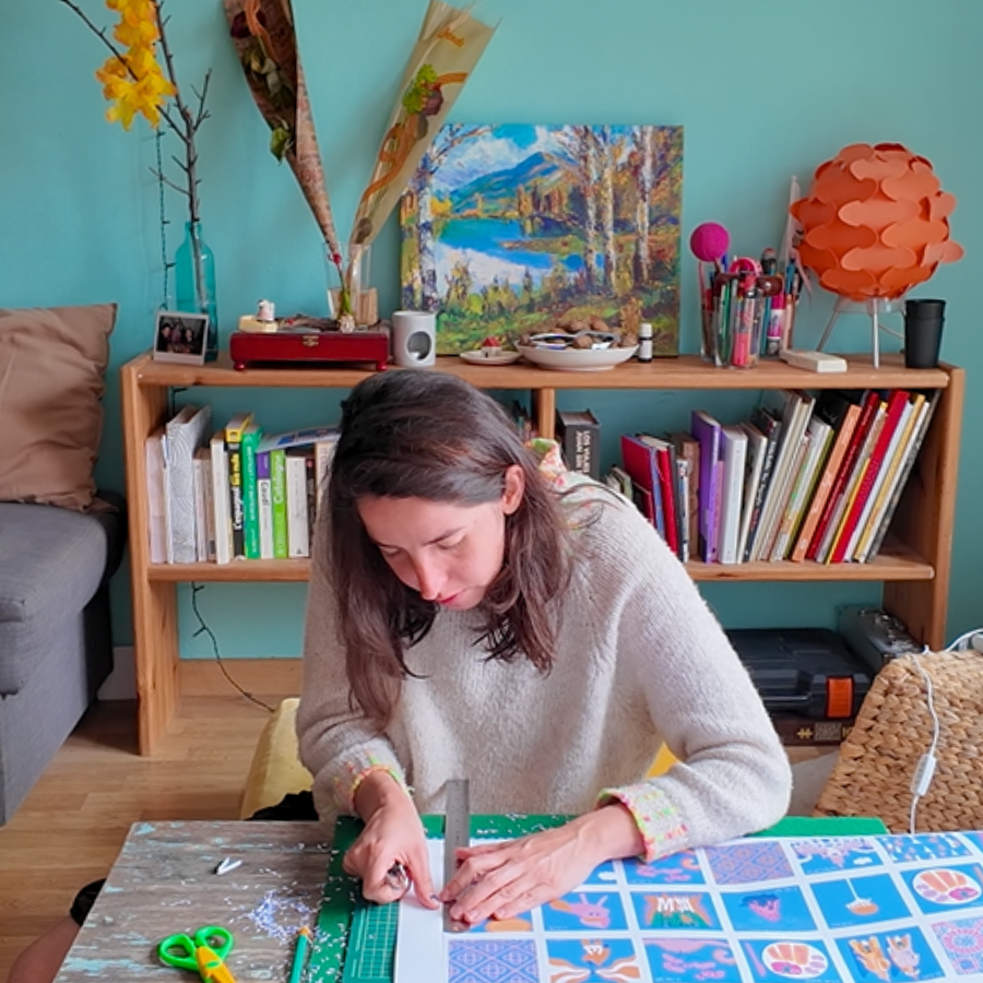 Amélie Decomble alias Amélimón en train de ttravailler dans son bureau. Elle découpe des illustrations qu'elle a faite elle même pour le clients skyscanner. Bureau trés joli, coloré. Illustration sur Barcelone